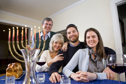 Jewish family celebrating Chanukah at table with menorah