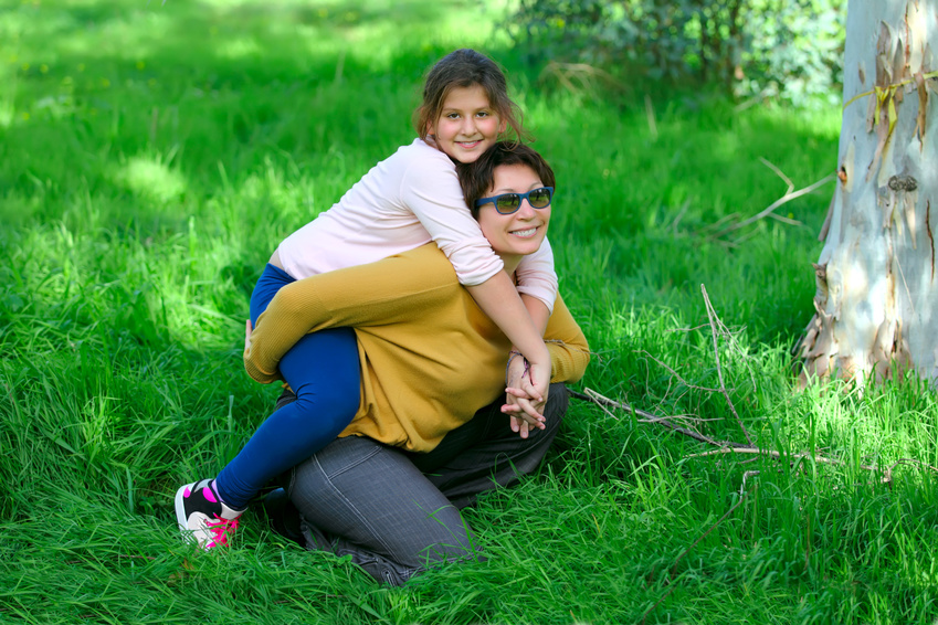a mother and a daughter on the green grass in a park